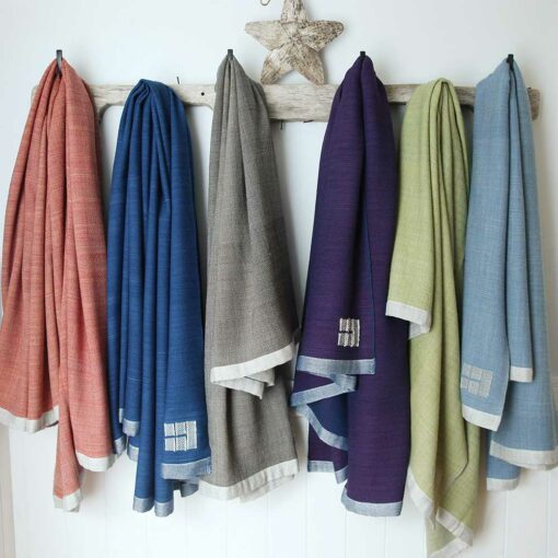 Swans Island's handwoven merino wool Katahdin Throws in assorted hand-dyed colors, hanging from pegs