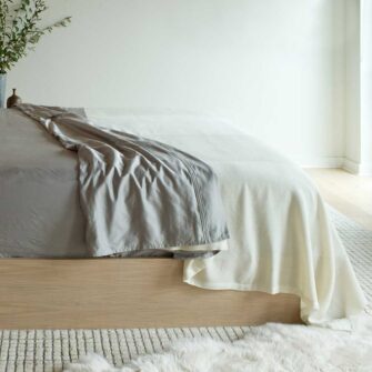 Swans Island handwoven solstice Blanket shown here in White + White. Subtle wide bands of white textured wool run head to foot on a king bed.