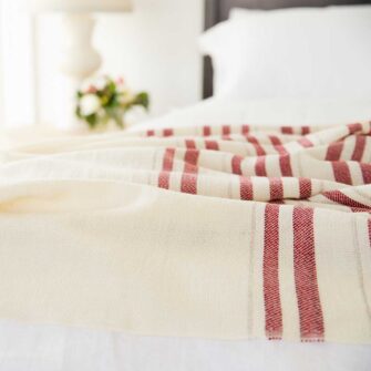 Swans Island Grace Blanket. Handwoven in Maine. 100% wool. Shown here in natural with red tripes on a king bed.
