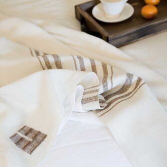 Swans Island Grace Blanket. Handwoven in Maine. 100% wool. Shown here in natural with brown stripes.