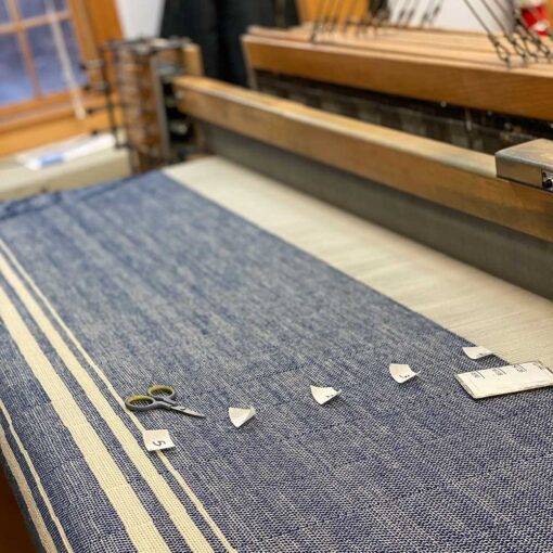 Handwoven clot on the loom at the Swans Island studio in Northport, Maine. Handwoven Grace Winter Blanket on the loom. Shown here in Natural + Indigo.