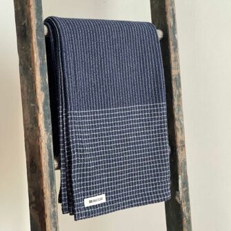 Swans Island's Pinstripe Throw blanket is woven in Maine with a blend of soft American cotton and linen. Shown in Navy.