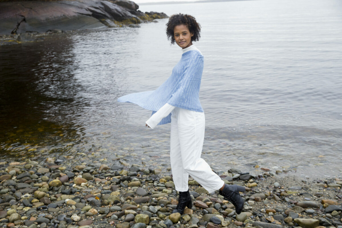 A model wears a Swans Island Firefly Ruana knit with hand-dyed merino wool and silk yarns.