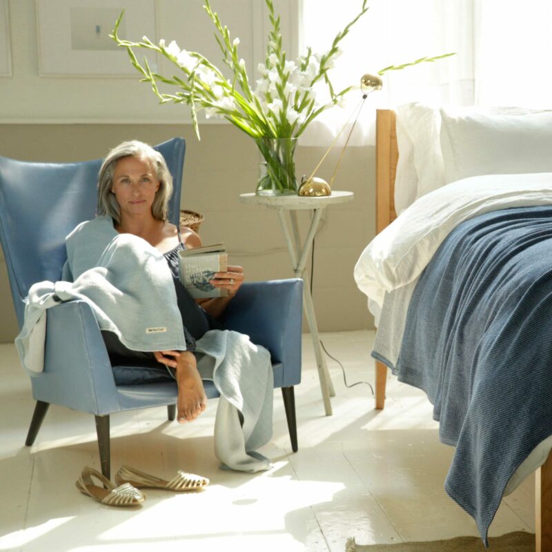 Swans Island Company's blanket and throw in shades of blue with white linen bedding.