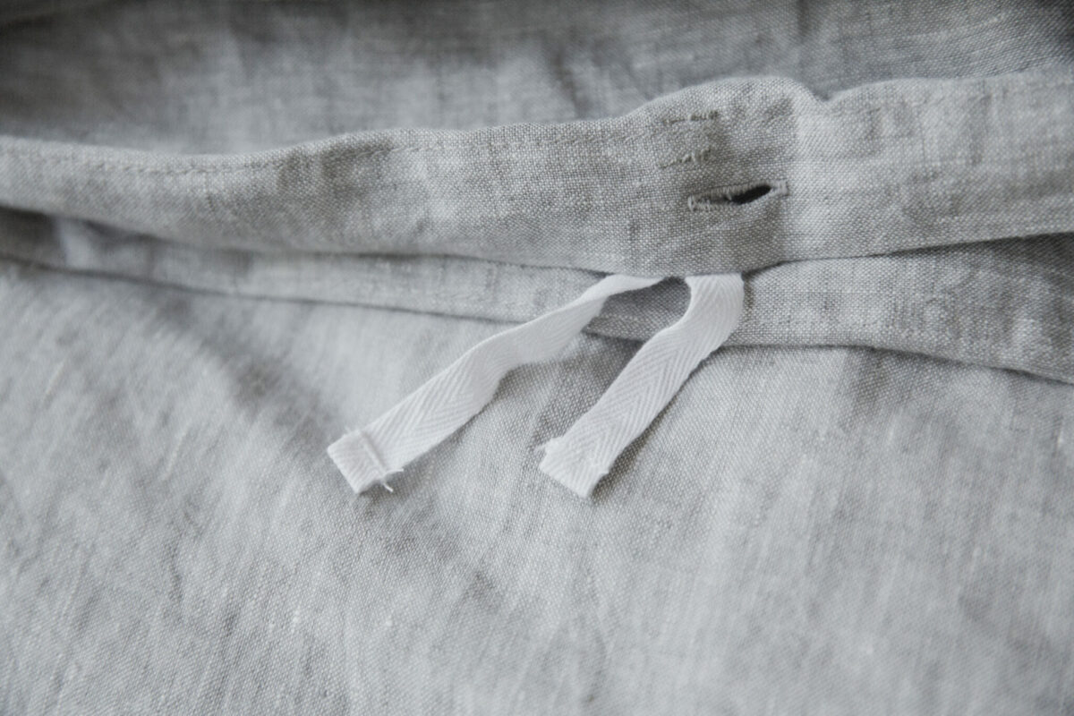 Detail of a French linen duvet cover showing buttonhole and interior ties.