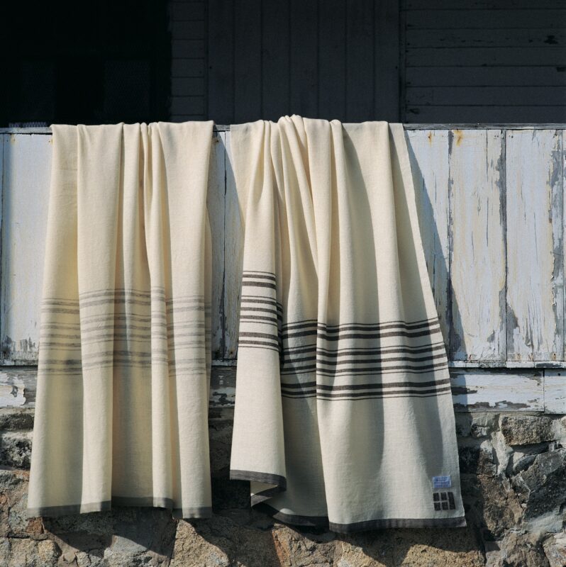 Two of the original blankets designs made by the Graces on Swans Island in the early 1990's. These traditional stripe patterns in white with undyed grey stripes, and white with natural brown stripes are still sold today by Swans Island Company.