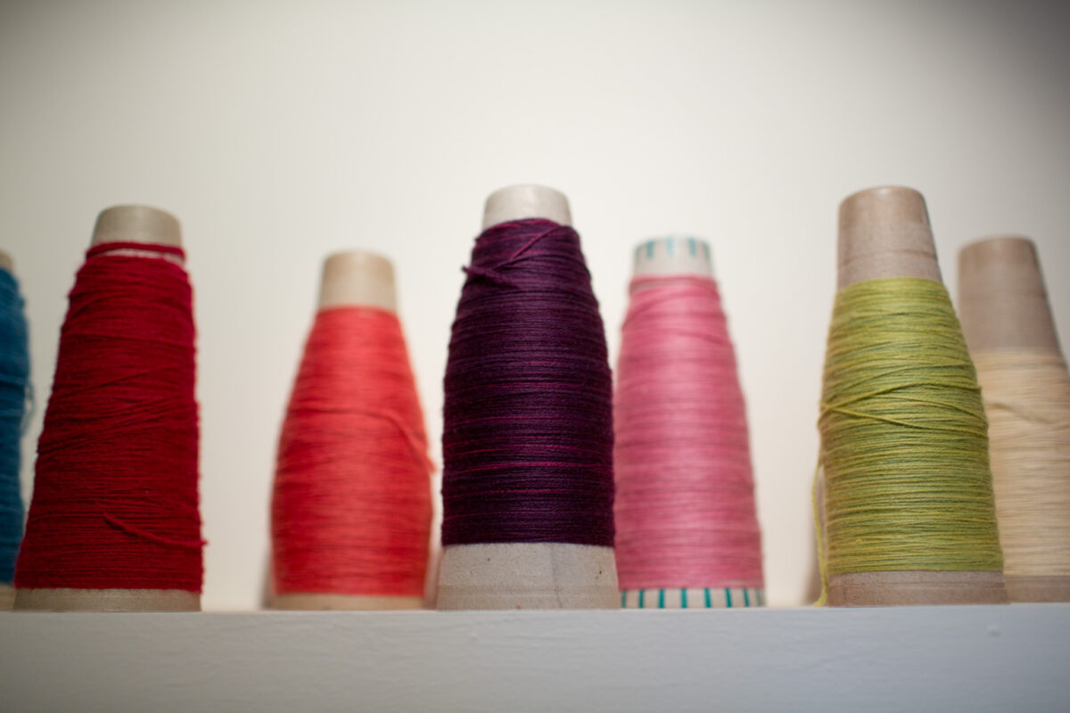 Colorful spools of yarns on the shelf at Swans Island's weaving studio. These colors are hand-dyed on organic merino wool using all natural dyes.