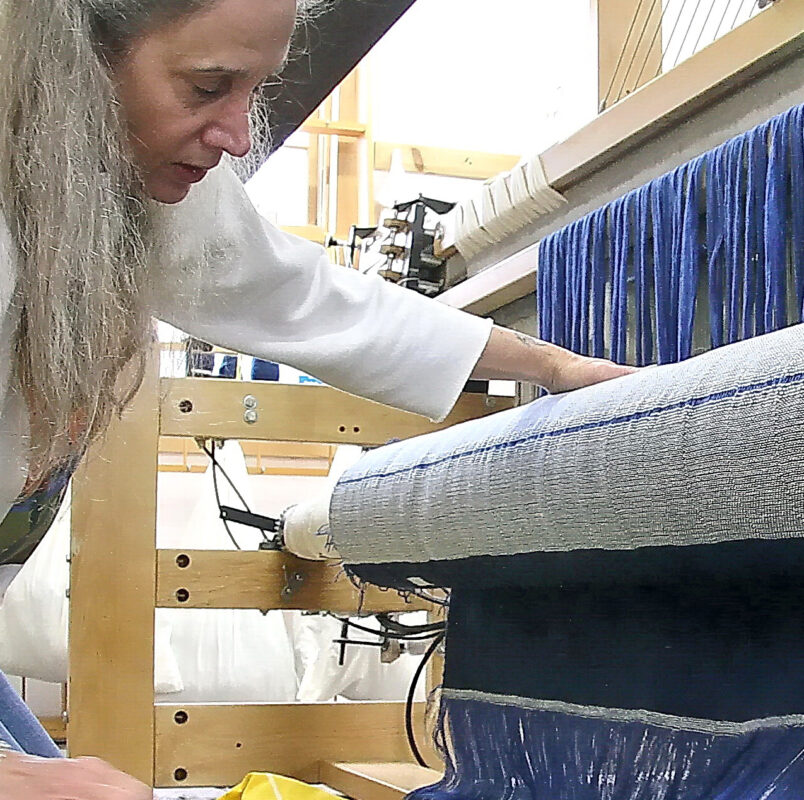 Carolyn Grace, one of the founders of Swans Island Company, in the very early days on Swans Island, taking handwoven cloth off the loom.