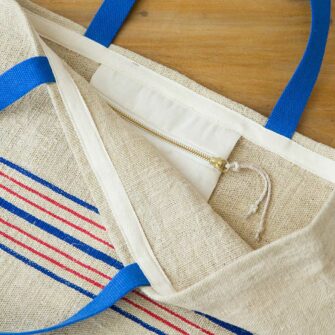 Swans Island Beach Tote by Govou is made from vintage European linen grain sacks. Shown here with red and blue stripes and blue shoulder straps.