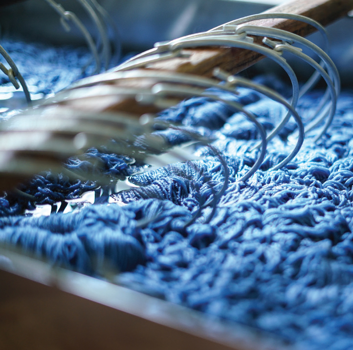 Skeins of merino wool yarn on rings soak in an indigo dye bath at the Swans Island dyehouse.
