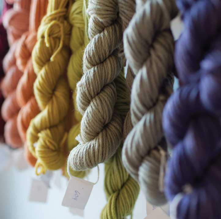 Colorful skeins of wool yarn dyed with all natural dyes hang in the Swans Island Company dyehouse test lab.