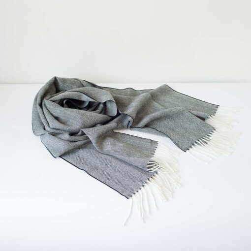 Swans Island Company's Baby Alpaca Scarf is woven in Peru with the softest baby alpaca. Lightweight and generously proportioned, this scarf has a classic herringbone twill pattern with fringed edges. . Shown here in Black with natural.