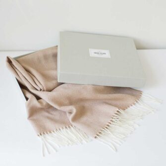 Swans Island Company's Baby Alpaca Scarf is woven in Peru with the softest baby alpaca. Lightweight and generously proportioned, this scarf has a classic herringbone twill pattern with fringed edges. . Shown here in Camel with natural in grey linen gift box.