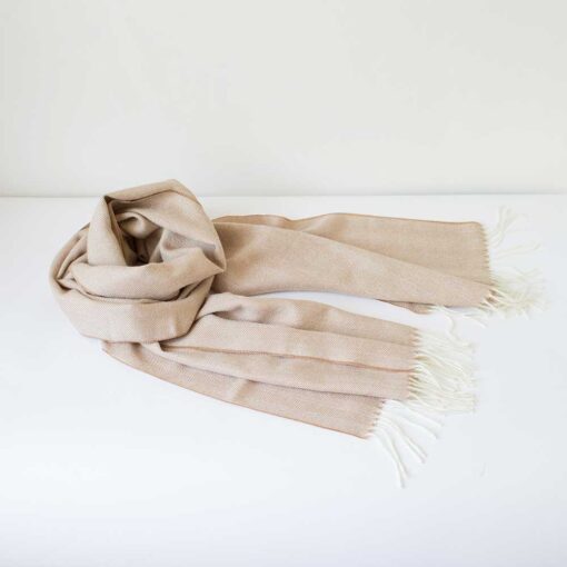 Swans Island Company's Baby Alpaca Scarf is woven in Peru with the softest baby alpaca. Lightweight and generously proportioned, this scarf has a classic herringbone twill pattern with fringed edges. . Shown here in Camel with natural.