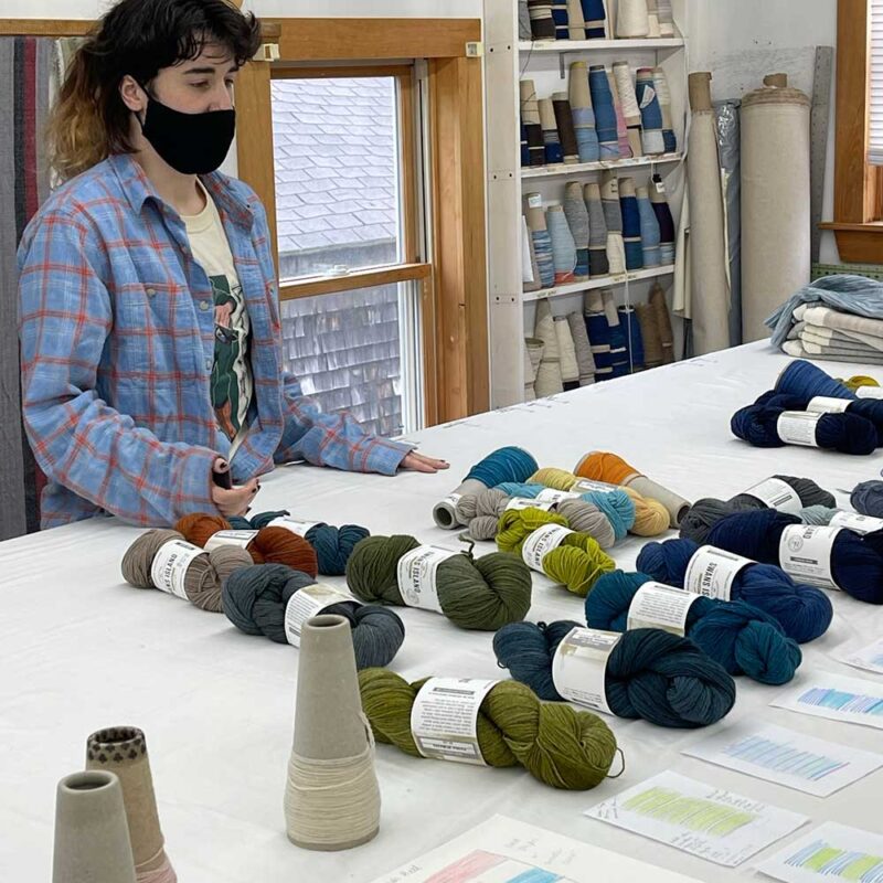 Riley works with an array of hand-dyed yarns on a table, in the design workshop for Swans Island Co. Ltd. Edition Ocean Throws.