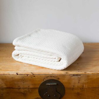 Swans Island Company's Charisma Blanket. Soft 100% Cotton blanket with woven herringbone texture. Made in USA with 100% American cotton. Shown here in Natural.