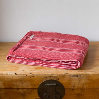 Swans Island Company's Cotton Pick Stripe Blanket. Soft 100% Cotton blanket with yarn-dyed woven stripes. Made in USA with 100% American cotton. Shown here in Berry Red.