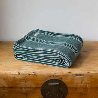 Swans Island Company's Cotton Pick Stripe Blanket. Soft 100% Cotton blanket with yarn-dyed woven stripes. Made in USA with 100% American cotton. Shown here in Hunter Green.