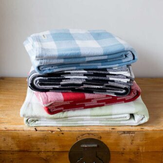 Swans Island Company's Cotton Gingham XL Check Blanket - woven in Maine on antique looms. Made with 100% soft American cotton. Shown here in Blue, Black, Red and Sage.