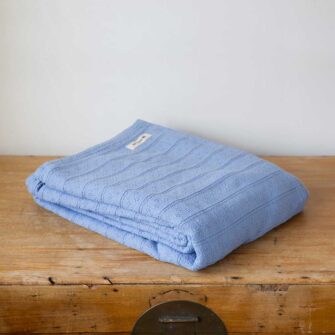Swans Island Company's Bedford Cotton Blanket. Soft 100% Cotton blanket with a small banded check texture. Made in Maine, USA with American cotton. Shown here in Light Blue.