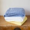 Swans Island Company's Bedford Cotton Blanket. Soft 100% Cotton blanket with a small banded check texture. Made in Maine, USA with American cotton. Shown here in Light Blue, White and Yellow.