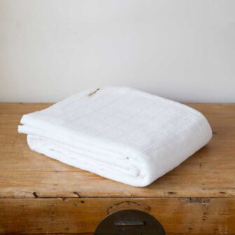 Swans Island Company's Bedford Cotton Blanket. Soft 100% Cotton blanket with a small banded checks texture. Made in Maine, USA with American cotton. Shown here in White.