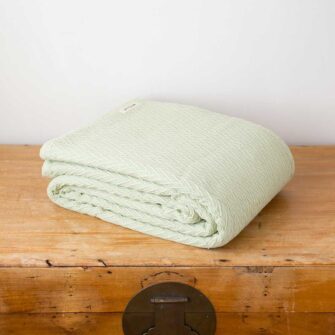 Swans Island Company's Charisma Blanket. Soft 100% Cotton blanket with woven herringbone texture. Made in USA with 100% American cotton. Shown here in Celadon.
