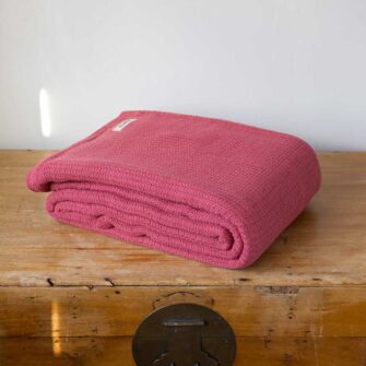 Swans Island Company's Tuscany Cotton Blanket. Soft 100% Cotton blanket woven with an allover basketweave texture. Made in Maine, USA. Shown here in Coral Red.