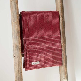 Company's Pinstripe Linen Throw. Made in USA, has an allover subtle pinstripe design highlighted with a checked border. Linen Cotton blend. Shown here in Currant color.