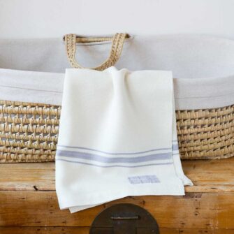 Swans Island Company's classic Grace Baby Blankets. Handwoven in Maine with soft organic merino wool yarns. Pure undyed organic merino wool with an assortment of rich hand-dyed stripe colors. Each blanket comes in a beautiful presentation gift box, perfect for gifting. Shown here in White with Dusk stripes.