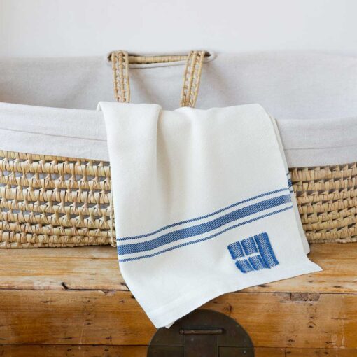Swans Island Company's classic Grace Baby Blankets. Handwoven in Maine with soft organic merino wool yarns. Pure undyed organic merino wool with an assortment of rich hand-dyed stripe colors. Each blanket comes in a beautiful presentation gift box, perfect for gifting. Shown here in White with Nautical Blue stripes.