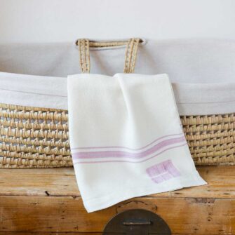 Swans Island Company's classic Grace Baby Blankets. Handwoven in Maine with soft organic merino wool yarns. Pure undyed organic merino wool with an assortment of rich hand-dyed stripe colors. Each blanket comes in a beautiful presentation gift box, perfect for gifting. Shown here in White with Rose Quartz stripes.