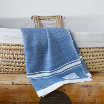 Swans Island Company's Modern Grace Baby Blankets. Handwoven in Maine with soft organic merino wool yarns in an assortment of rich hand-dyed colors. Each blanket comes in a beautiful presentation gift box, perfect for gifting. Shown here in Nautical Blue with natural stripes.