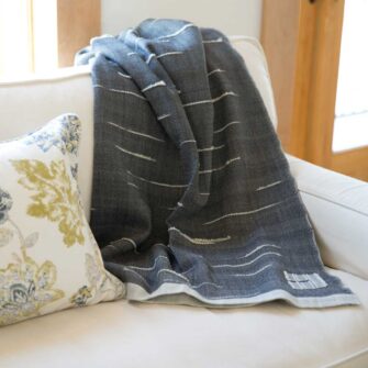 Swans Island Company's Whitecaps Throw is handwoven in Maine. Soft bits of wool roving handwoven into each throw recall whitecaps on the waters of Penobscot Bay. Shown here in Charcoal on a white soft.